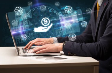 Borsada çalışan iş adamı dizüstü bilgisayardan çıkan bitcoin simgelerini veriyor