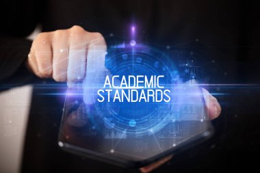 ACADEMIC STANDARDS yazıtlı, eğitici konseptli katlanabilir bir akıllı telefon tutan genç adam