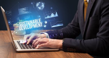 Sürdürülebilir Kalkınma yazıtları ve yeni iş kavramı ile dizüstü bilgisayarda çalışan işadamı