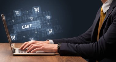 CART yazıtları ve online alışveriş konseptiyle birlikte dizüstü bilgisayarda çalışan bir işadamı