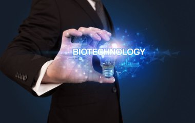 BIOTECHNOLOGY yazıtlı ampul tutan iş adamı, yenilikçi teknoloji kavramı