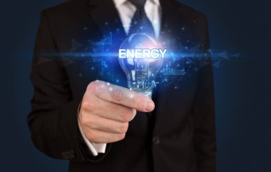 ENERGY yazıtlı, yenilikçi teknoloji kavramına sahip bir iş adamı elinde ampul tutuyor