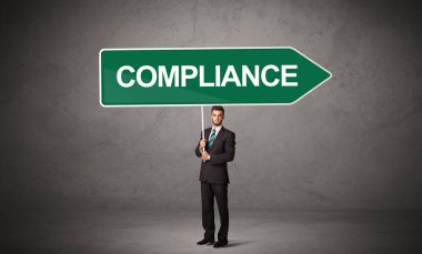 CommpLIANCE yazıtları, yeni iş yönü konsepti ile günlük bekleme yolu tabelasında genç iş adamı