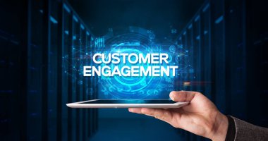 Tablet üzerinde çalışan genç iş adamı ve yazıyı gösteriyor: CUSTOMER ENGAGEMENT, iş konsepti