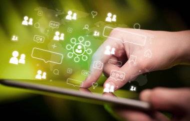 Toplum ağları simgeleri içeren tablet kullanan bir elin yakın plan resmi, sosyal medya kavramı