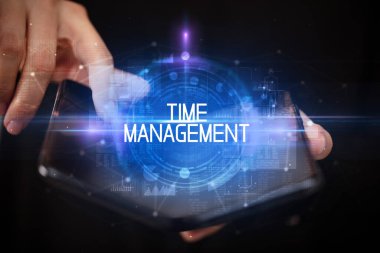 Time ManageMENT yazıtlı, eğitici konseptli katlanabilir bir akıllı telefon tutan genç adam.