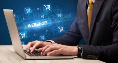 Webshop yazıtları ve online alışveriş konseptiyle çalışan bir iş adamı.