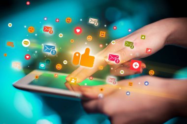 Renkli tablet kullanan bir elin yakın plan görüntüsü, ondan çıkan simgeler gibi, sosyal ağ konsepti
