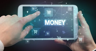 El ele tutuşma tabletinin yakın plan fotoğrafı. Üzerinde para yazılı, online alışveriş konsepti var.