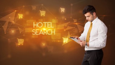 Alışveriş arabası ikonları ve otel arama yazıları olan bir işadamı, online alışveriş konsepti.