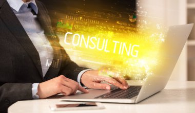 CONSULTING yazıtları ve başarılı iş konsepti ile birlikte dizüstü bilgisayarda çalışan iş adamlarının yakınlaşması