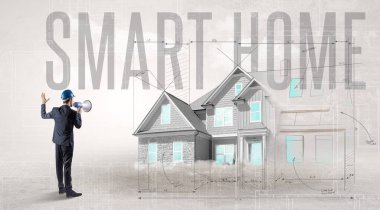 Genç mühendis elinde SMART HOME yazıtları ve ev planlama konsepti olan planları tutuyor.