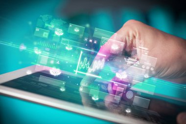 Grafik simgeleri içeren tablet kullanan bir elin yakın plan görüntüsü, dijital para birimi kavramı