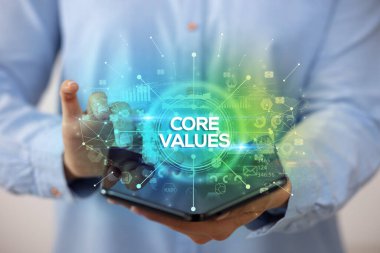 İş adamı elinde Core Values yazısıyla katlanabilir bir akıllı telefon tutuyor, yeni iş konsepti