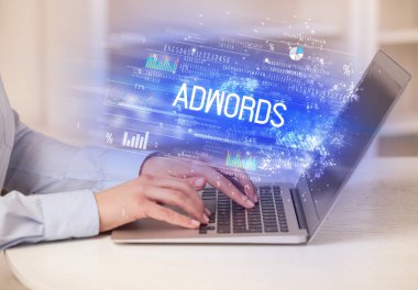 ADWORDS yazıtları ve başarılı iş konseptiyle birlikte dizüstü bilgisayarda çalışan iş adamlarının yakınlaşması