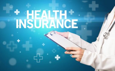 Doktor panoya HeALTH INSURANCE yazısını, ilk yardım kavramını içeren notlar yazar.