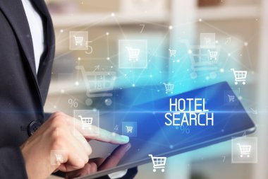 Genç kişi, HOTEL Arama yazısıyla online alışveriş uygulaması üzerinden alışveriş yapıyor