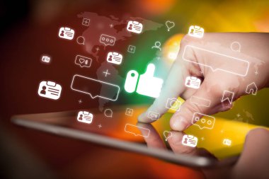 İçinden ikonlar çıkan tablet kullanan bir elin yakın plan resmi, sosyal medya kavramı