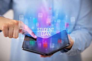 Öğrenci Kredisi ve eğitim konsepti içeren katlanabilir bir akıllı telefon tutan genç adam.