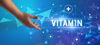VITAMIN yazıtlarına işaret eden kırpılmış elin yakın çekimi, tıbbi konsept