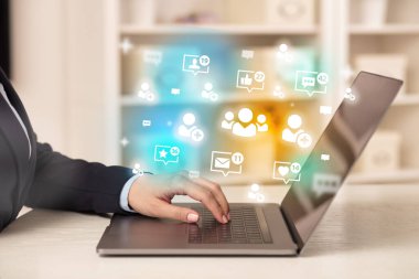 Toplum simgeleriyle dizüstü bilgisayarda sörf yapan genç kişi, sosyal medya kavramı