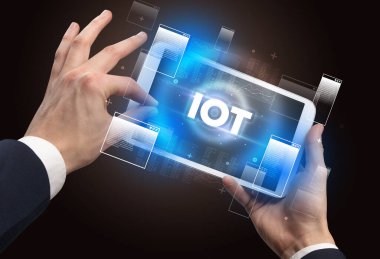 IOT kısaltması ile el ele tutuşma tableti, modern teknoloji konsepti