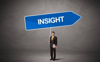 Genç iş adamı, içinde INSIGHT yazıtları ve yeni iş yönü kavramı olan günlük bekleme yolu tabelasında.