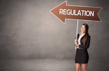 Genç iş adamı, günlük bekleme yolu tabelasında REGULATION yazıtları, iş yönü konsepti