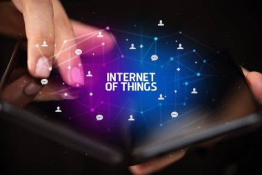 İş adamı elinde, üzerinde yeni teknoloji kavramı ve yazıtların olduğu katlanabilir bir akıllı telefon tutuyor.