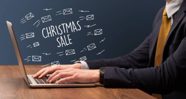 Yılbaşı indirimi ve online alışveriş konseptiyle dizüstü bilgisayarda çalışan bir işadamı.