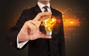 İş adamı elinde MACHINE İLKETİ, İş teknolojisi konsepti kavramı kavramını öğrenen bir ampul tutuyor