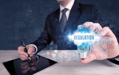 İş adamı elinde Regulasyon yazıtlı bir ampul tutuyor, yeni iş konsepti