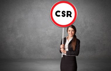 Genç iş adamı CSR kısaltması ve teknoloji çözüm kavramına sahip trafik tabelasını elinde tutuyor