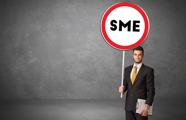 stock image Young business person holdig traffic sign with SME abbreviation, technology solution concept