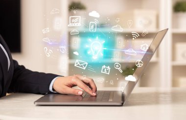 Dizüstü bilgisayarda çalışan iş adamı, içinden ampul simgeleri çıkıyor ve iş dünyası kavramı büyüyor.