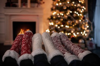 Bir şöminenin yanında ısınan aile ayaklarını kapat.