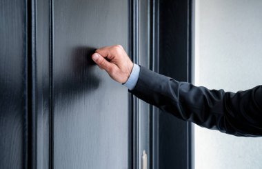 Close up of young man knocking on the door with copy space clipart