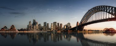 Gün batımında Sydney şehir merkezi ve Harbour Köprüsü panoramik görünümü 