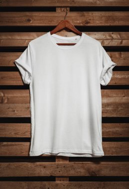 Kopya alanı ile ahşap arka plan asılı boş beyaz t-shirt 