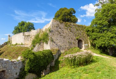Hohenurach Castle in Bad Urach near Stuttgart, Germany. Landscape of mountain forest, sky and fortress walls overgrown by ivy. Old German castle ruins, Tourist attraction of Swabian Alps in summer.