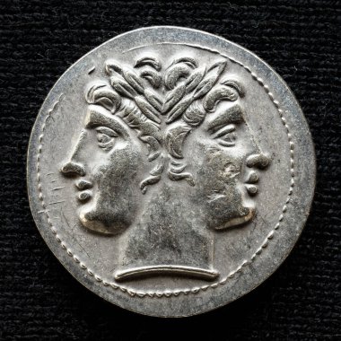 Ancient coin showing two-headed Roman god Janus, 225-214 BC. Old rare money, silver didrachm isolated on dark background, macro. Concept of Rome, valuable coin, past civilization and history. clipart