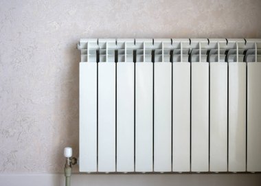 Heating radiator on light wall background, white metal water heater in home room. Concept of warmth, energy crisis, saving, contemporary radiator.