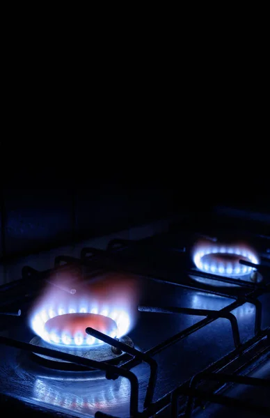 Propane gas burns on dark background with black copy space, vertical view of gas stove and blue fire flame of burners. Concept of gas cost, Gazprom, energy crisis, payment, economy, Nord Stream 2.