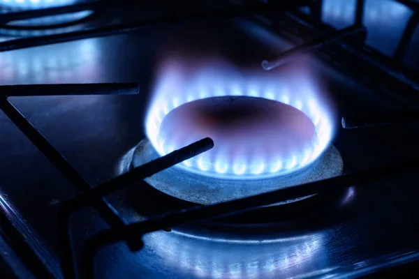 Gas burns in dark at home, blue fire flame of stove ring burners. Concept of natural pipeline gas cost and payment, energy crisis in Europe, supply in Germany, EU economy, Gazprom and Nord Stream 2.