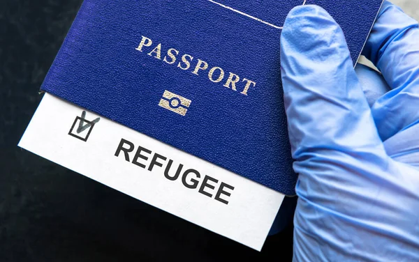 Refugee passport in hand at border control in Europe, document with refugee note close-up. Concept of Ukraine war, Syria, EU, humanitarian crisis, migration and emigration.