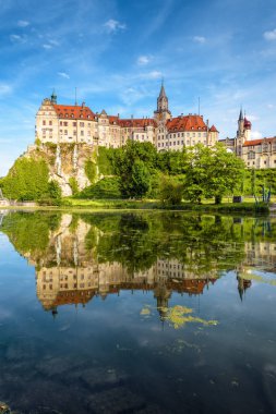 Sigmaringen Castle, Baden-Wurttemberg, Germany. Vertical view of Hohenzollern house from Danube river. Scenery of German mansion with mirror reflection and blue sky, landmark of Schwarzwald in summer