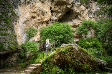 Person walks in gorge, Kislovodsk, Russia. Mountain landscape with Honey Waterfalls in summer, tourist attraction. Theme of nature, travel, tourism, hike and forest in Caucasus Mineral Waters.