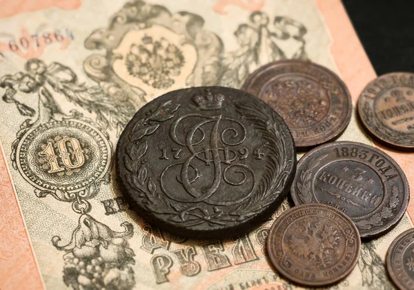 Russian Empire coins and vintage paper money note of 19th cent. Old copper coins of Russia, monogram of Catherine the Great in center. Concept of antique currency, rare coins and coat of arms.