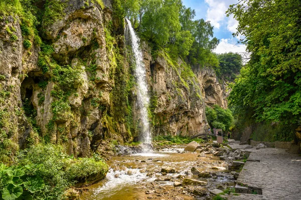 Waterfall in Kislovodsk, Russia. Water falls into gorge, mountain landscape with rocks, canyon and trees in summer. Theme of nature, travel, hike, forest and tourism in Caucasus Mineral Waters.