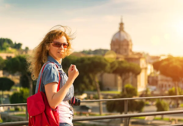 Tourist girl walks in Rome, Italy, Europe. Young pretty woman looks at camera in Rome at sunset. Person wearing sunglasses travels across Roma city. Tourism, attraction, lifestyle and beauty concept.